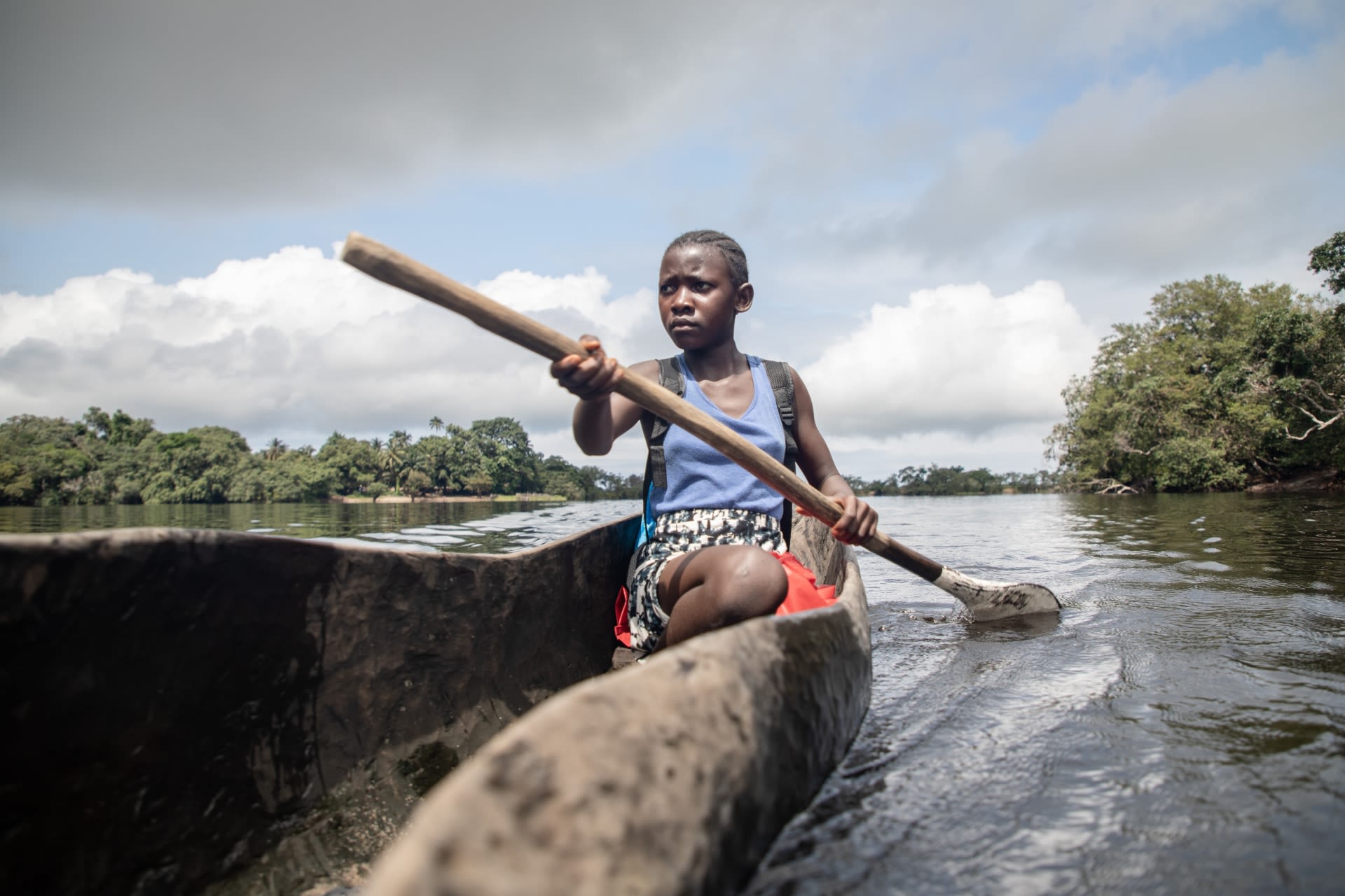 Tenneh, aged 13, paddling her wooden canoe to school in Pujehun district, Sierra Leone.