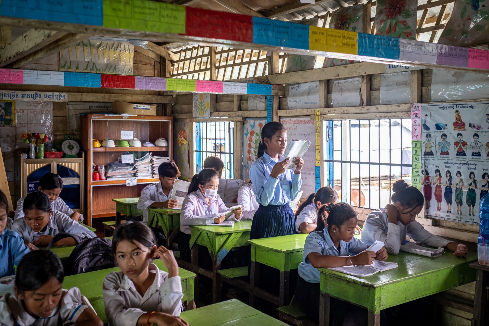 Ratana, 12, at her school on Tonle Sap Lake, Cambodia. She is reading from a book to the class as the other students follow along.