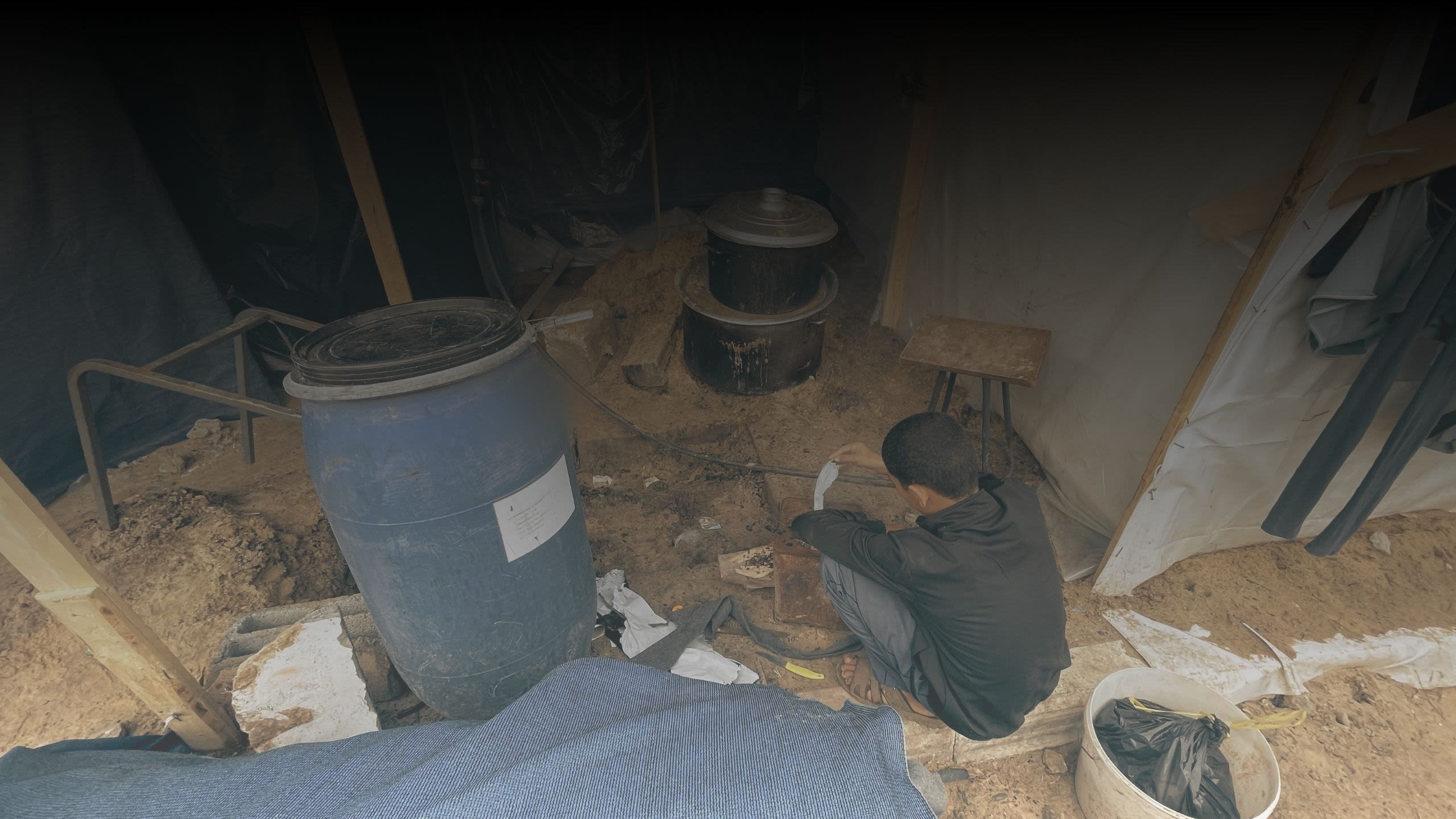 A teenager sits by a stove in a shelter in Gaza.