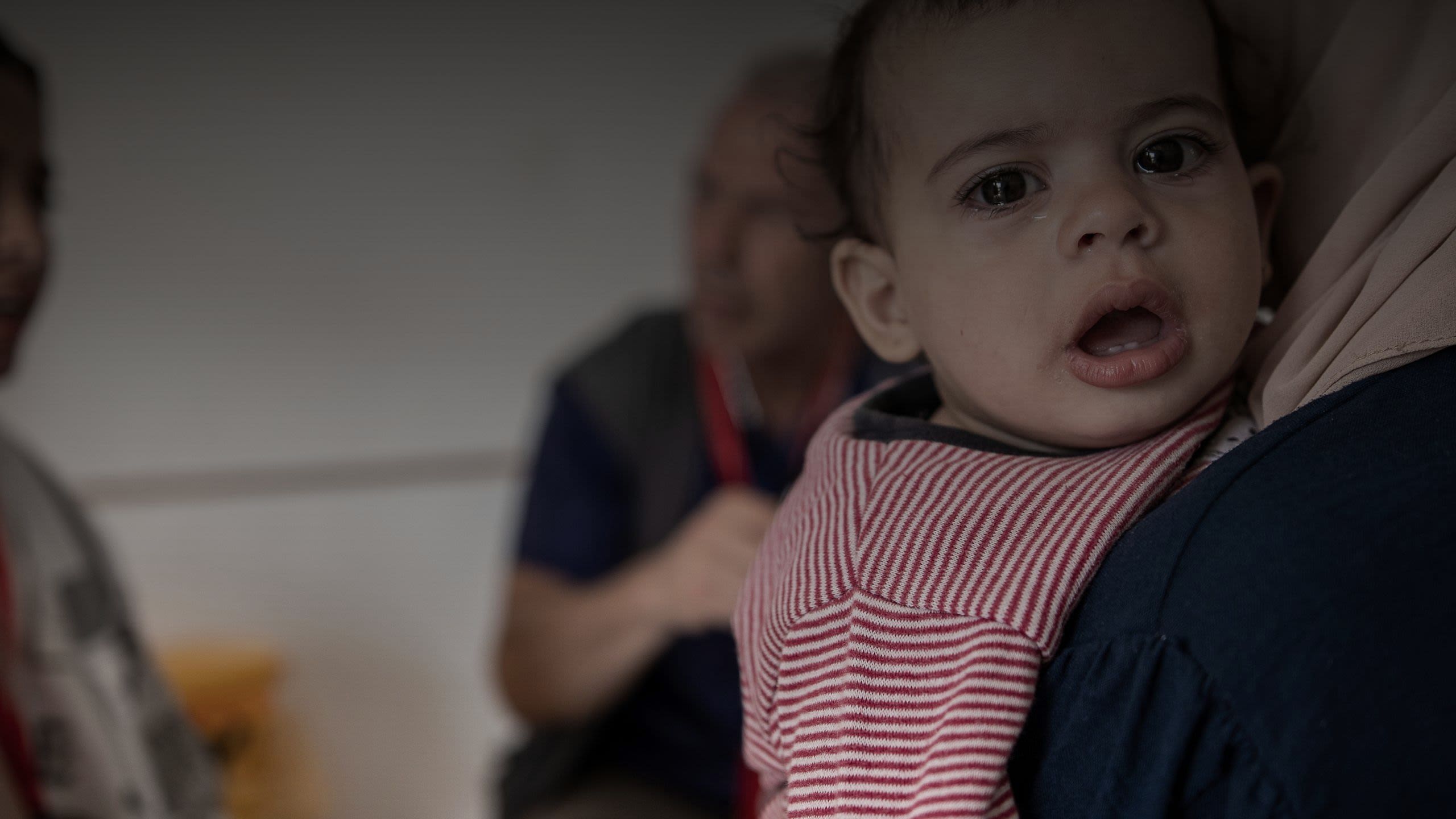 Masah (1) is held by her mother while she is treated by a doctor at the Emergency Health Unit field hospital.
